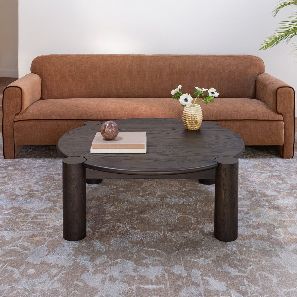 Table basse organique moderne en chêne massif avec plateau rond à bord arrondi et pieds colonne pour salon