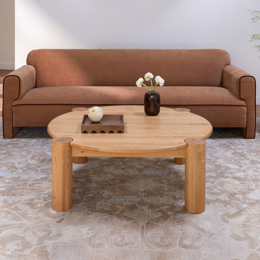 Table basse organique moderne en chêne massif avec plateau rond à bord arrondi et pieds colonne pour salon
