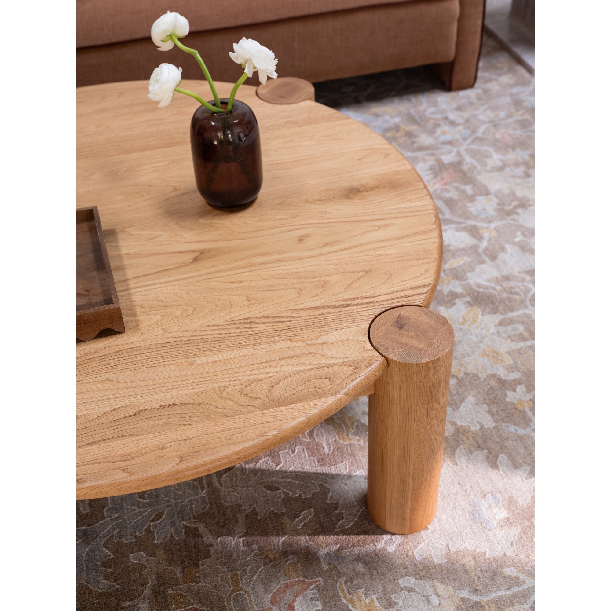 Table basse organique moderne en chêne massif avec plateau rond à bord arrondi et pieds colonne pour salon